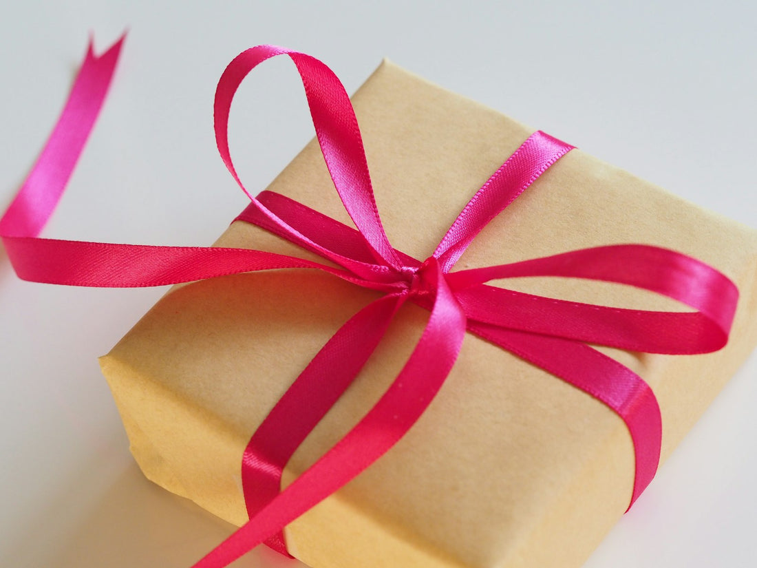 Una caja de regalo envuelta en papel madera con un moño rosa