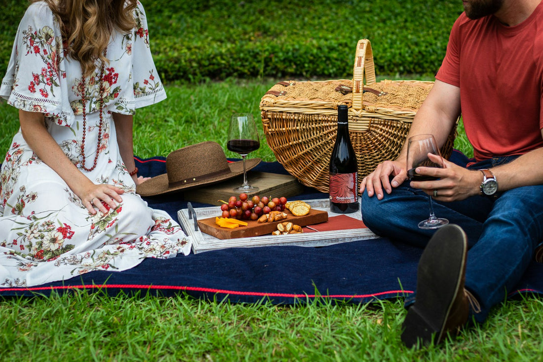 Una pareja hace un picnic sobre una manta con una canasta