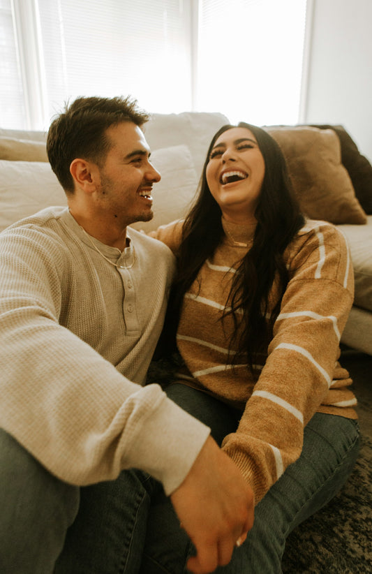 Una pareja se ríe abrazada en el sofá