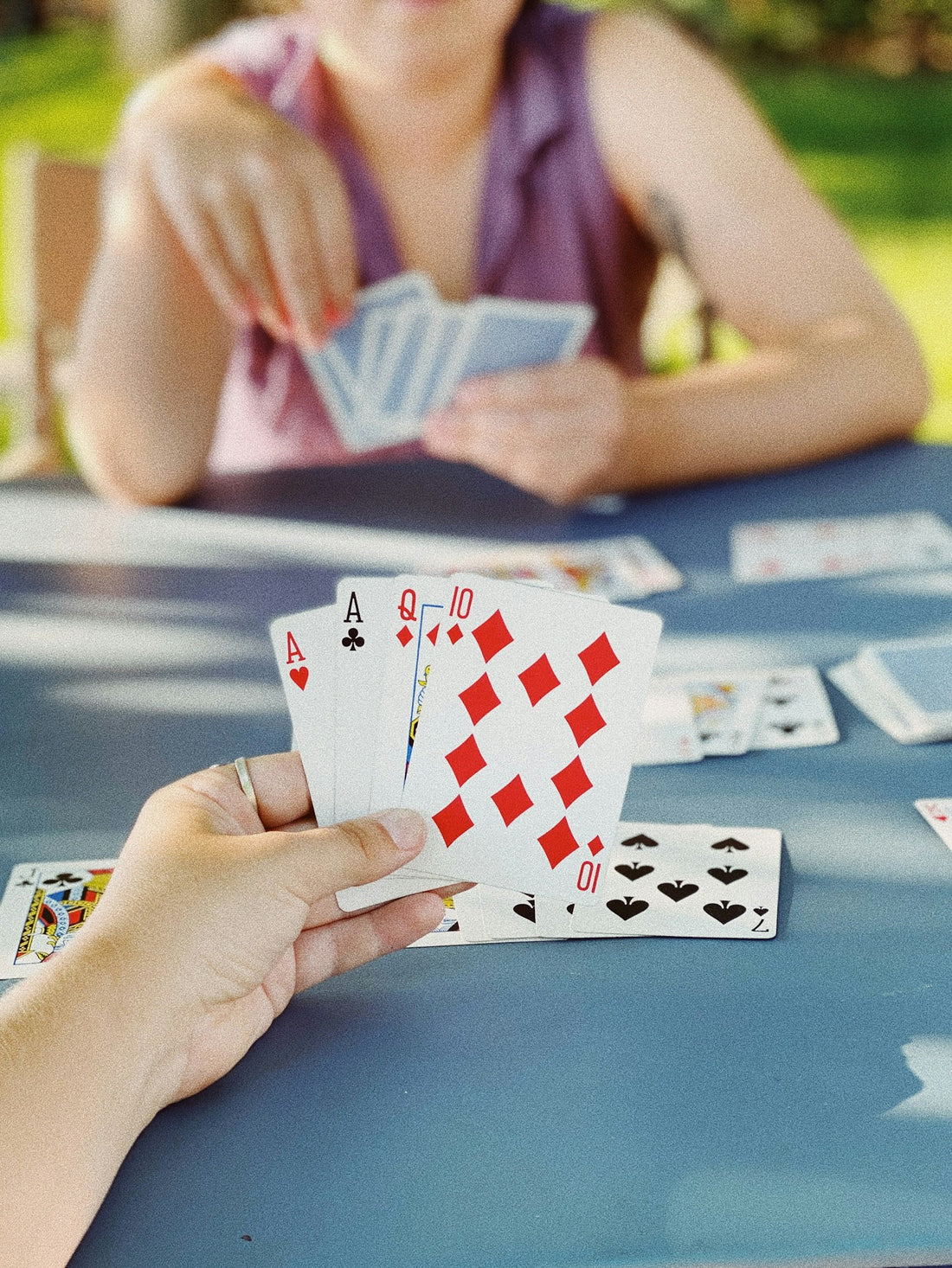 Manos sostienen cartas sobre una mesa durante una partida