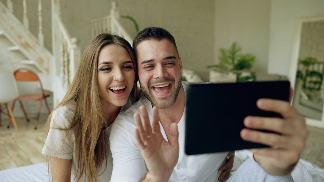 Una pareja se saluda sonriendo en una videollamada desde una tablet