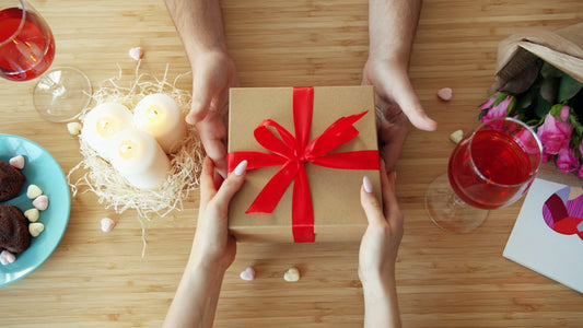 Dos pares de manos intercambian un regalo con un moño rojo