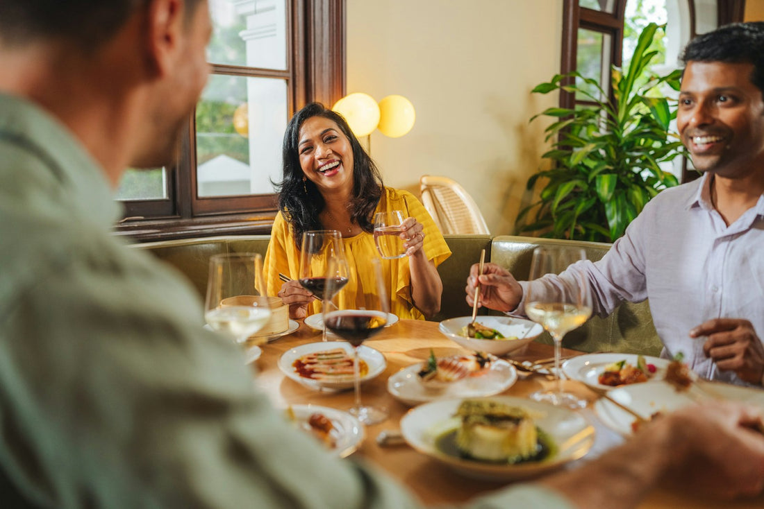Tres amigos se ríen mientras comen en una mesa de restaurante